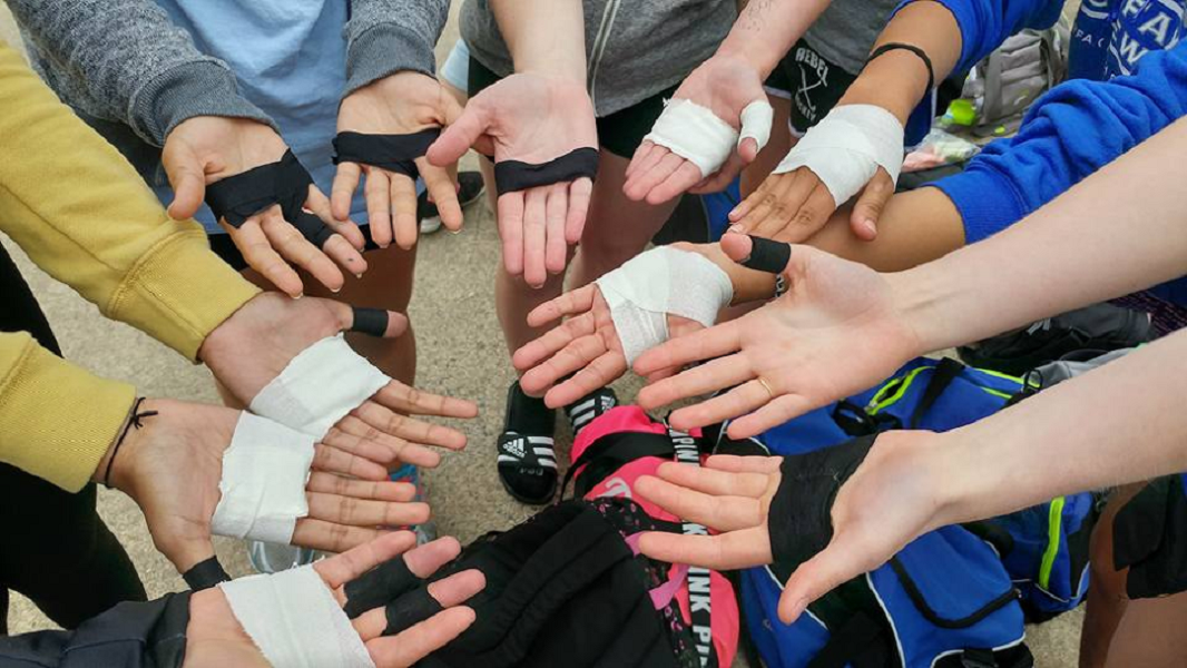 A group of athletes displaying different techniques for taping hands:  using elastic stretch tape, rigid tape, and even kinesiology tape to protect their hands