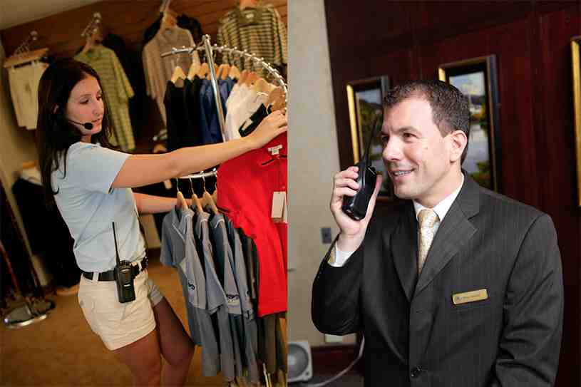 smiling guest checking in with hotel staff seamlessly coordinating in background using radios - hospitality radios (hotels, restaurants)