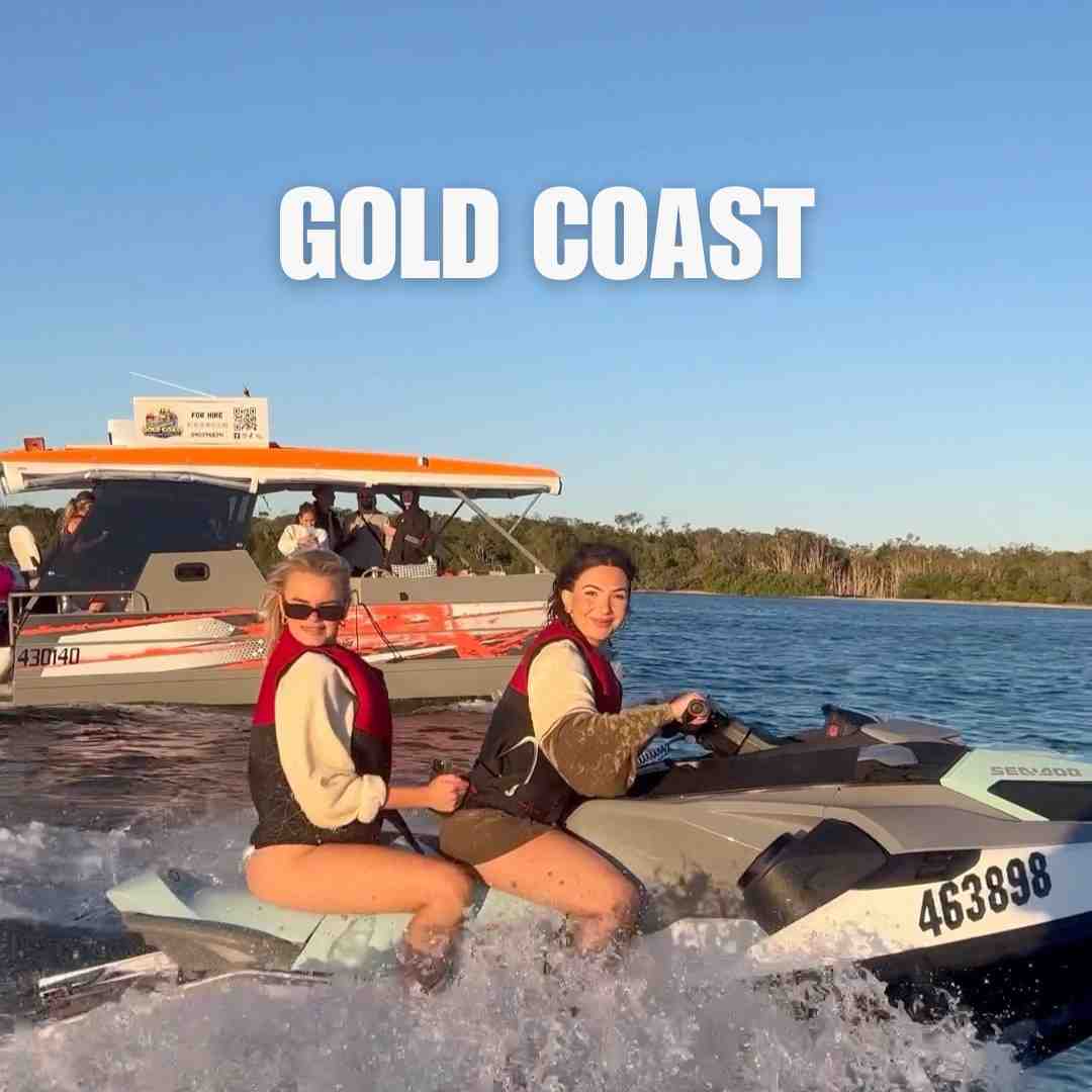 Two happy women riding a jet ski next to a hire boat on a summer Gold Coast Christmas cruise adventure.