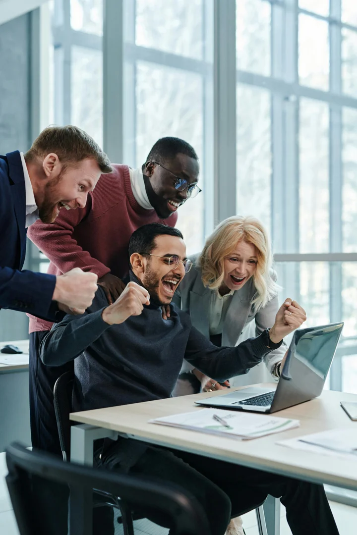 Business team celebrating success with Dynamics 365 Sales data.