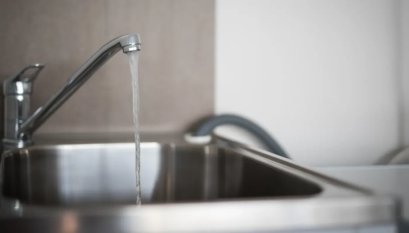 A homeowner collecting a water sample from a kitchen faucet in Rhode Island - How to Test Your Water Quality in RI
