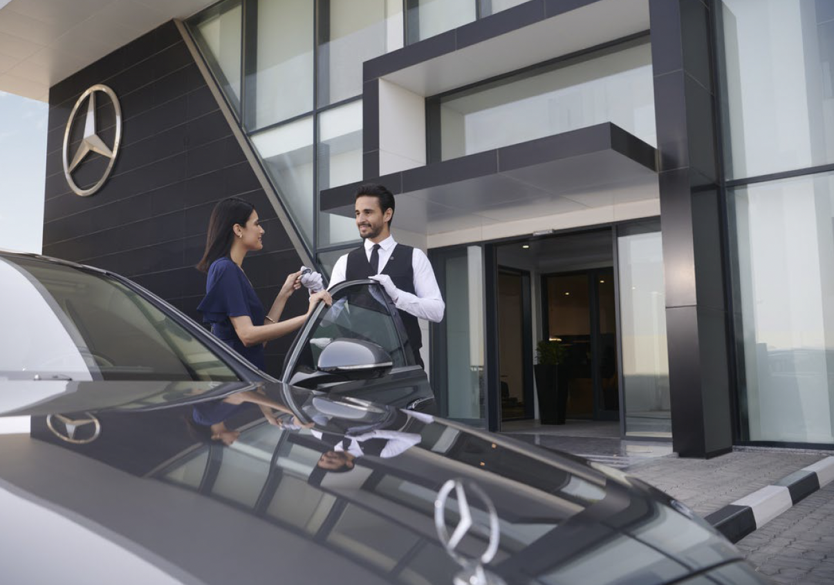A sophisticated individual, takes ownership of her new Mercedes-Benz vehicle taking her new keys from the white-gloved Benzel-Busch Associate after securing certified pre-owned financing 