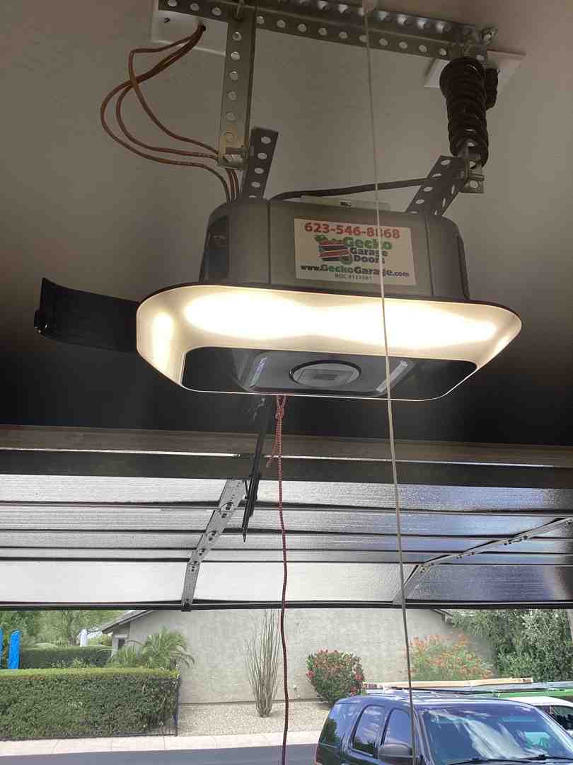 Friendly technician in Gecko Garage Doors uniform installing garage door opener - LiftMaster belt drive opener