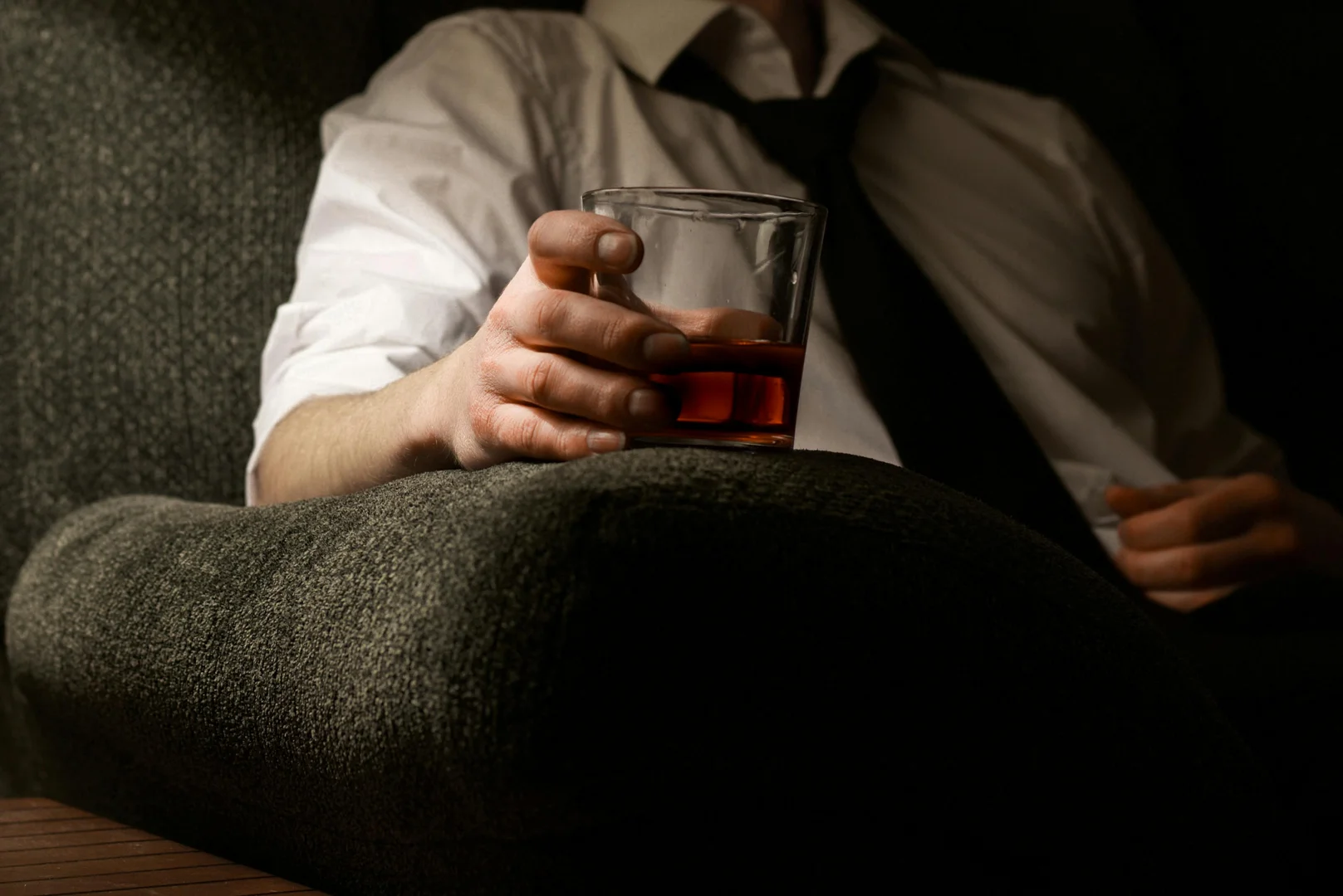 Half-body portrait of a man holding a glass containing an alcoholic beverage 
