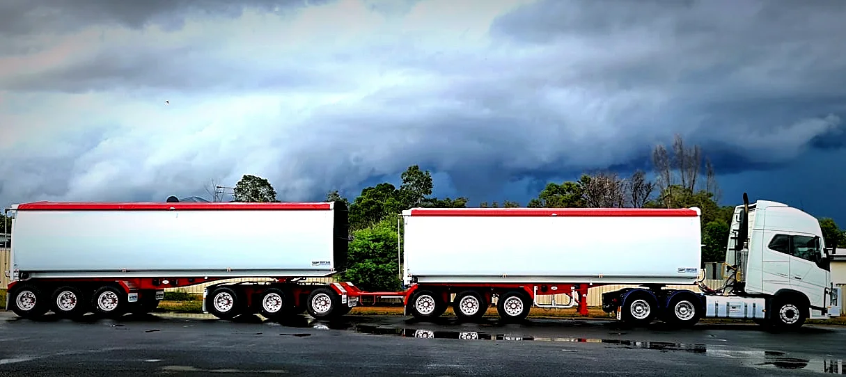 A B-double truck with red and white trailers featuring retractable tarp covers for expert load containment Australia.