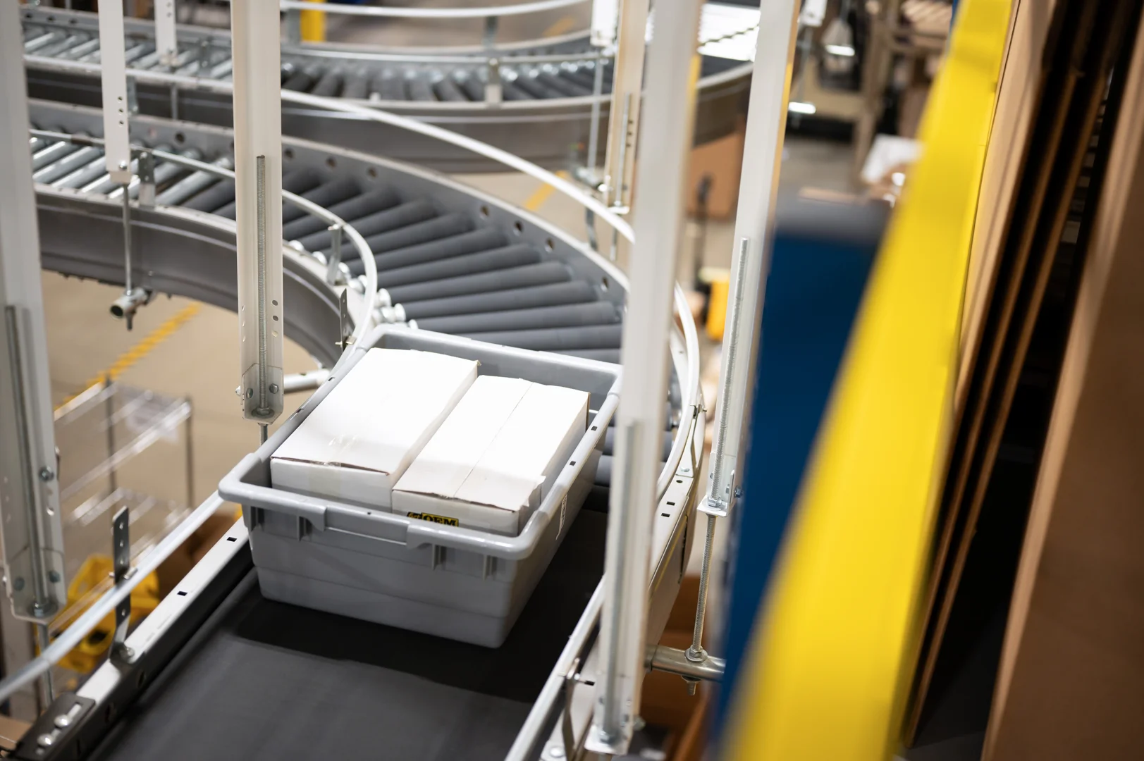 Modern warehouse interior with a conveyor belt material handling system moving cardboard boxes.