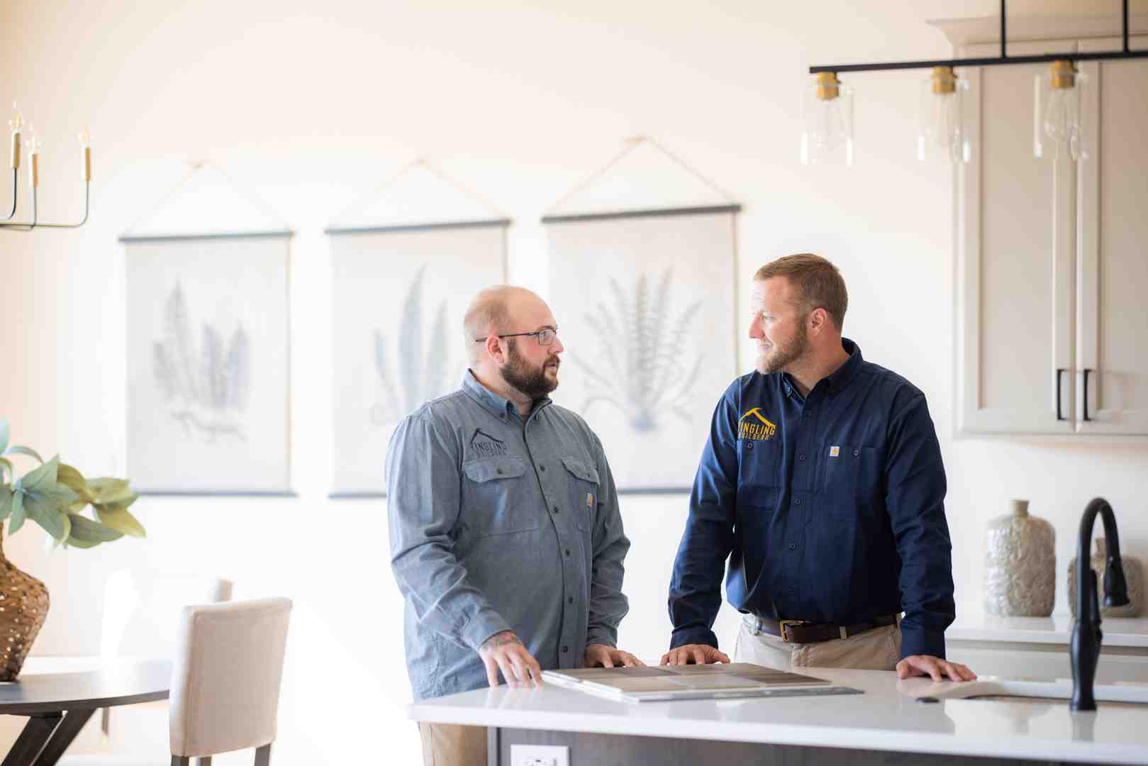 A happy couple reviewing architectural plans with a professional home builder inside a bright modern custom kitchen A happy couple reviewing architectural plans with a professional home builder inside a bright modern custom kitchen