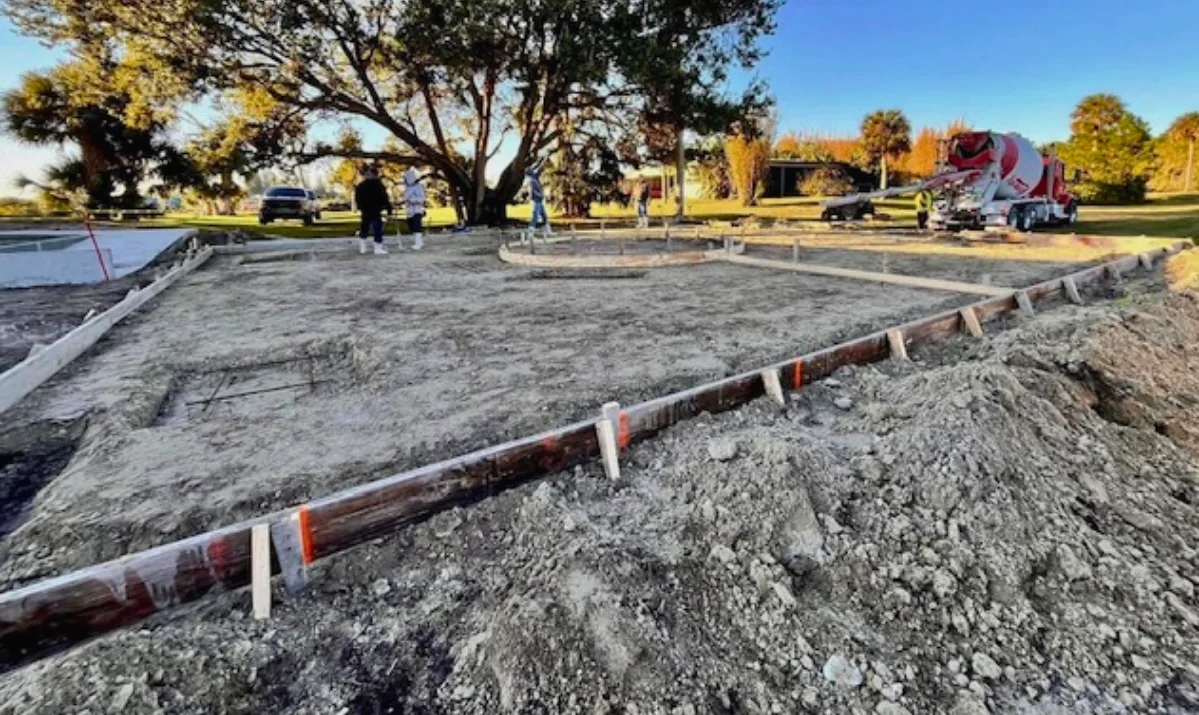 Commercial concrete foundation site preparation with forms set and ready-mix truck on site