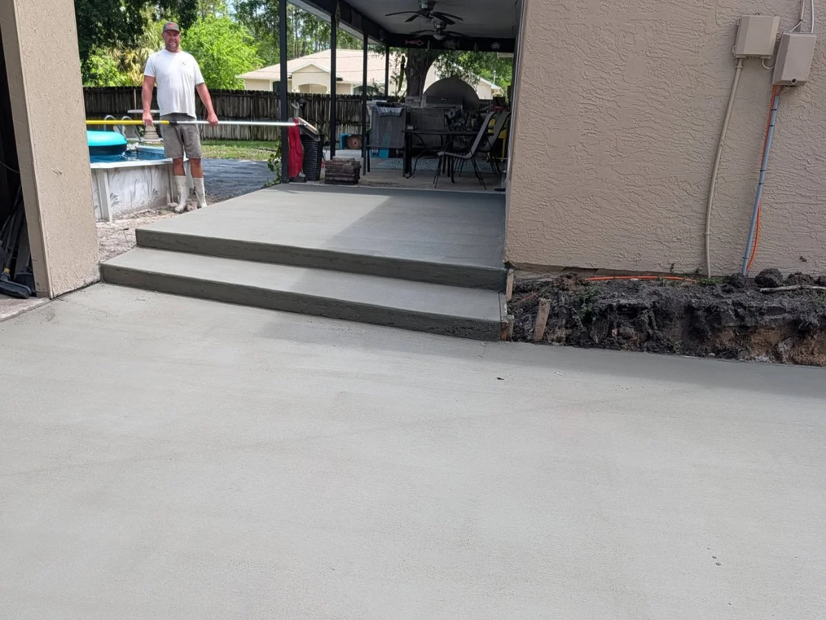 Freshly poured concrete patio with steps beside a Florida home