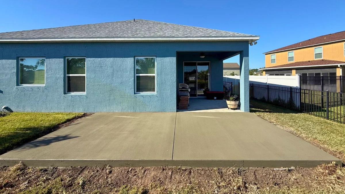Finished backyard concrete patio slab connected to a covered rear porch of a Florida home