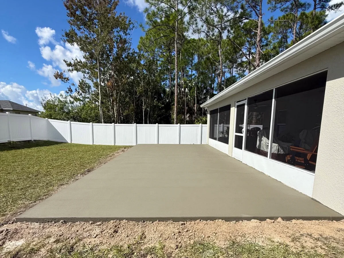 Finished backyard concrete patio slab beside a screened Florida home