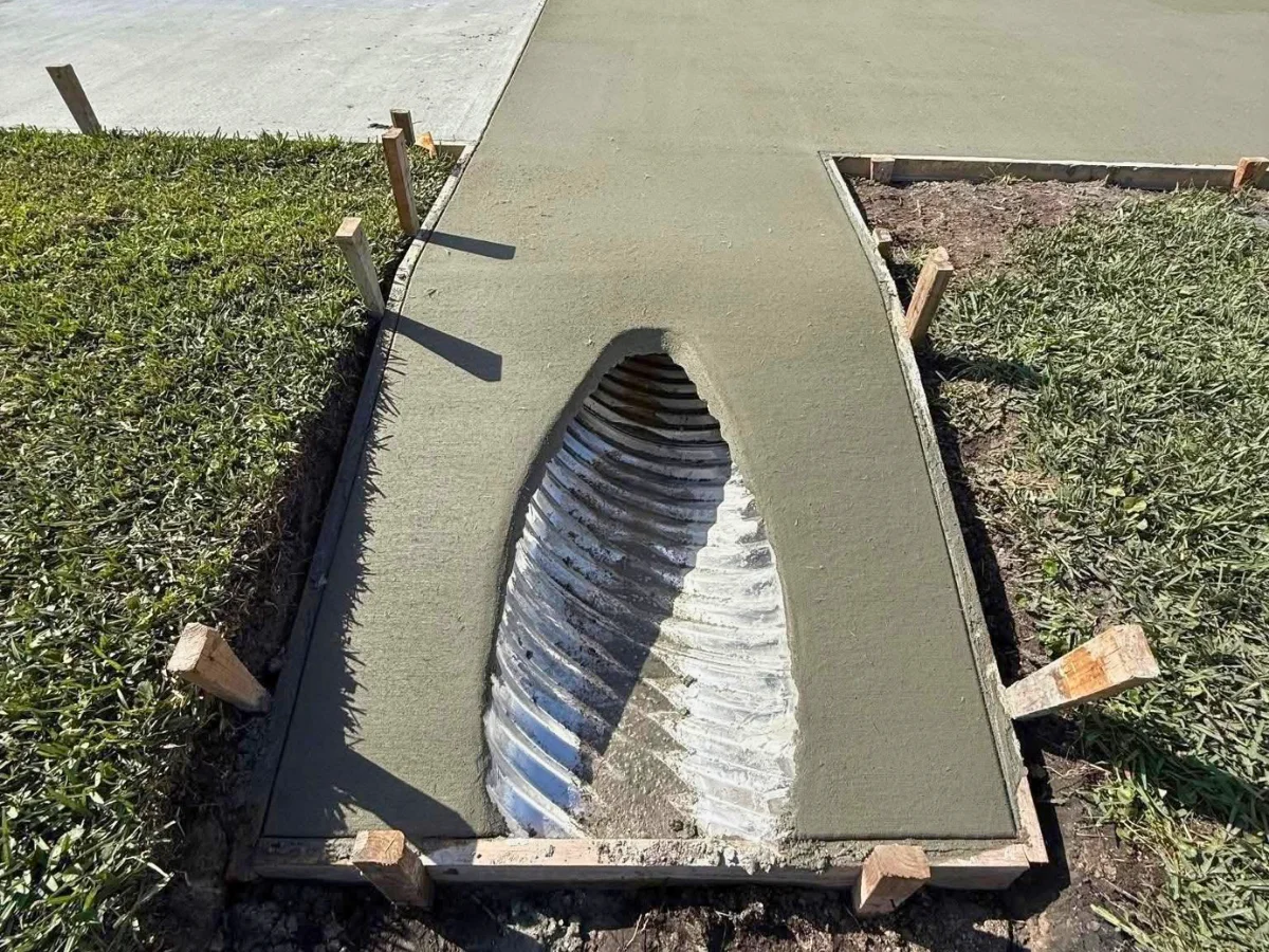 corrugated drainage pipe under driveway concrete with fresh concrete poured around culvert opening