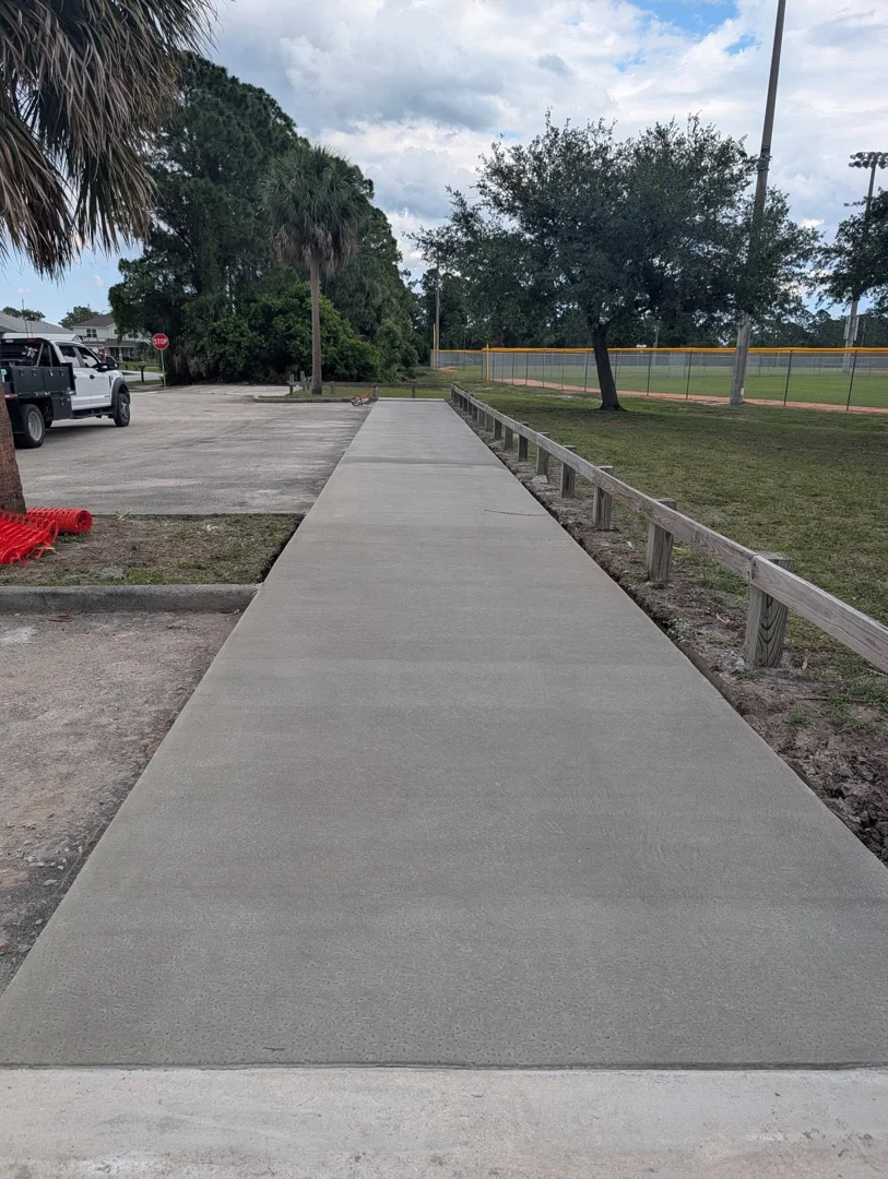 Finished concrete sidewalk beside a recreation field