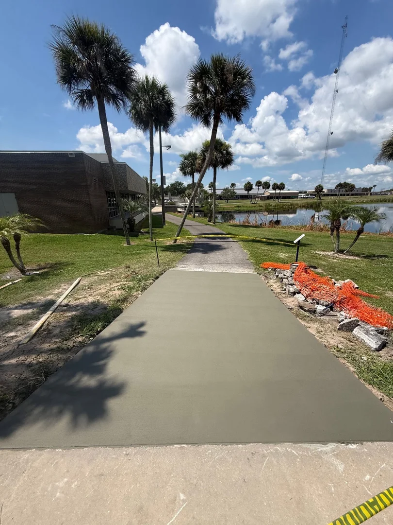 New concrete walkway beside a building and pond New concrete walkway beside a building and pond