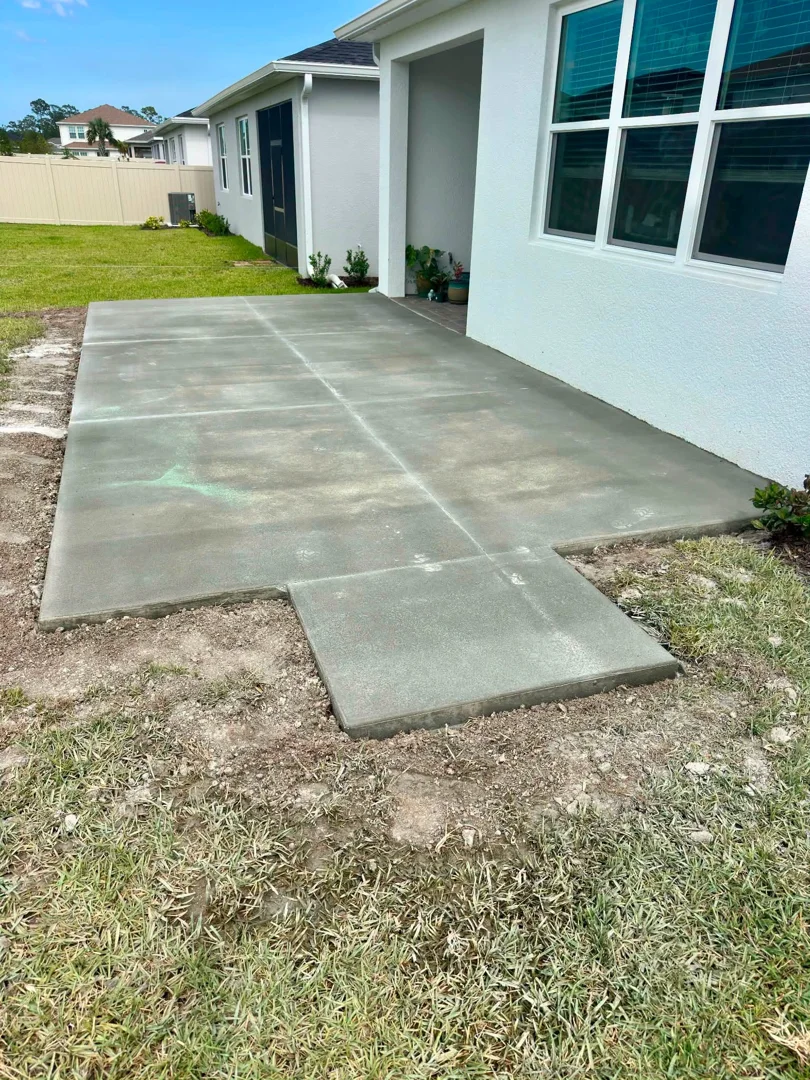Residential concrete patio slab beside a home with a connecting walkway Residential concrete patio slab beside a home with a connecting walkway