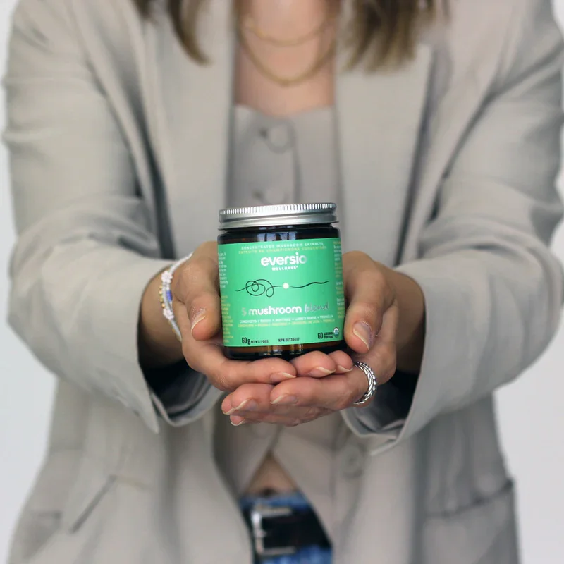 Hands holding the '5 Mushroom Blend' jar, containing the beauty-boosting tremella mushroom supplement and other potent fungi.