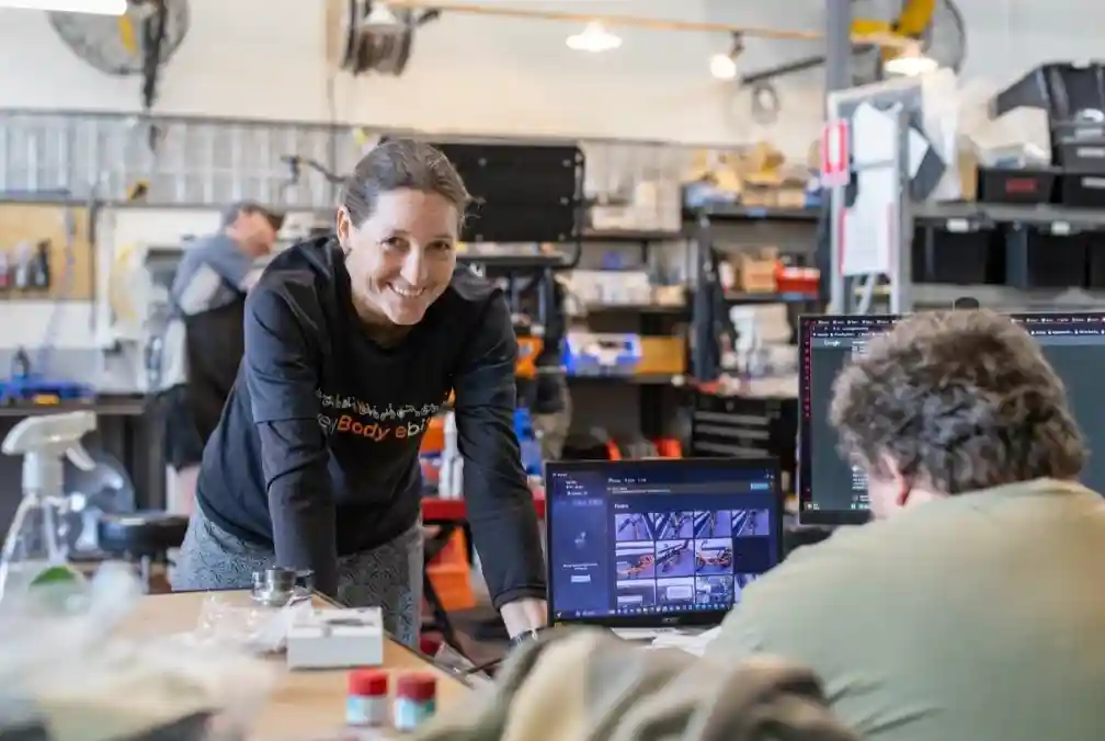 a friendly mechanic in the EveryBody eBikes workshop giving a thumbs-up next to a serviced electric trike - electric tricycle servicing