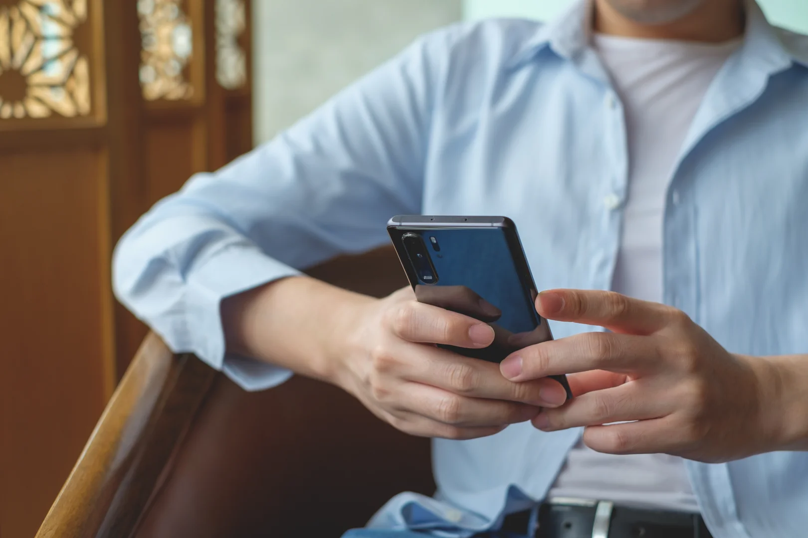 Man using smartphone to coordinate worker transport logistics for remote sites.