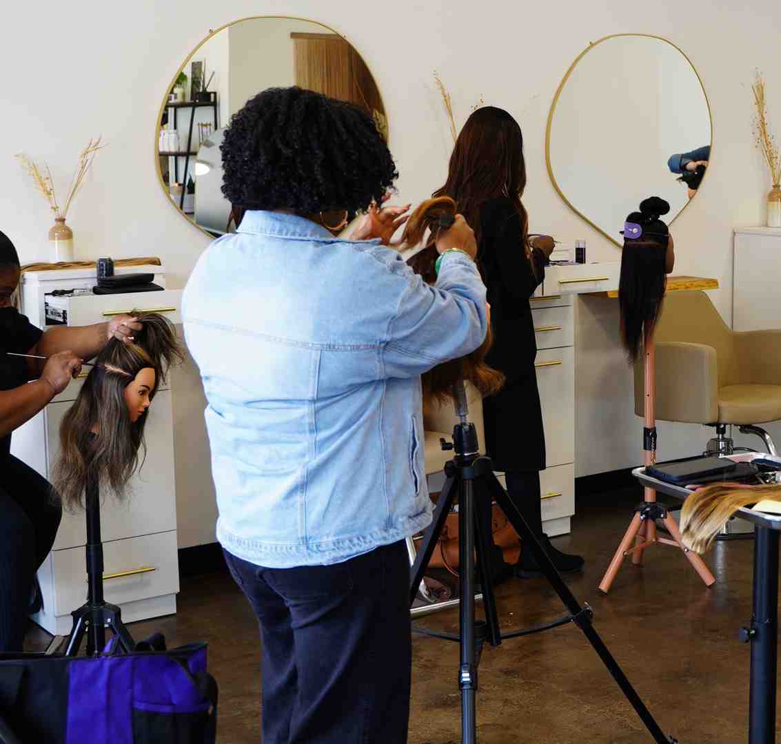 Hands-on certification class showing stylists learning proper extension techniques with mannequin heads and professional tools - hair extension store near me