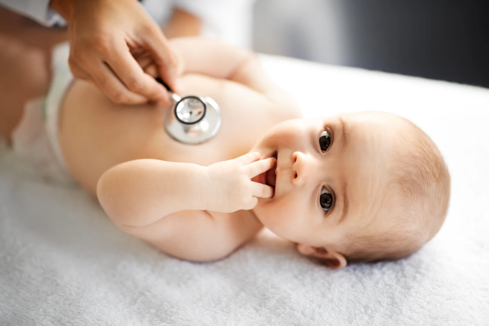user-inserted A smiling baby having their heartbeat listened to by a doctor's stethoscope.