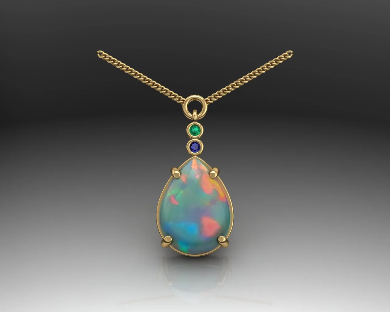 A custom-designed birthstone necklace containing a pear-shaped opal accented by a smaller round blue sapphire and round emerald on a gold chain.