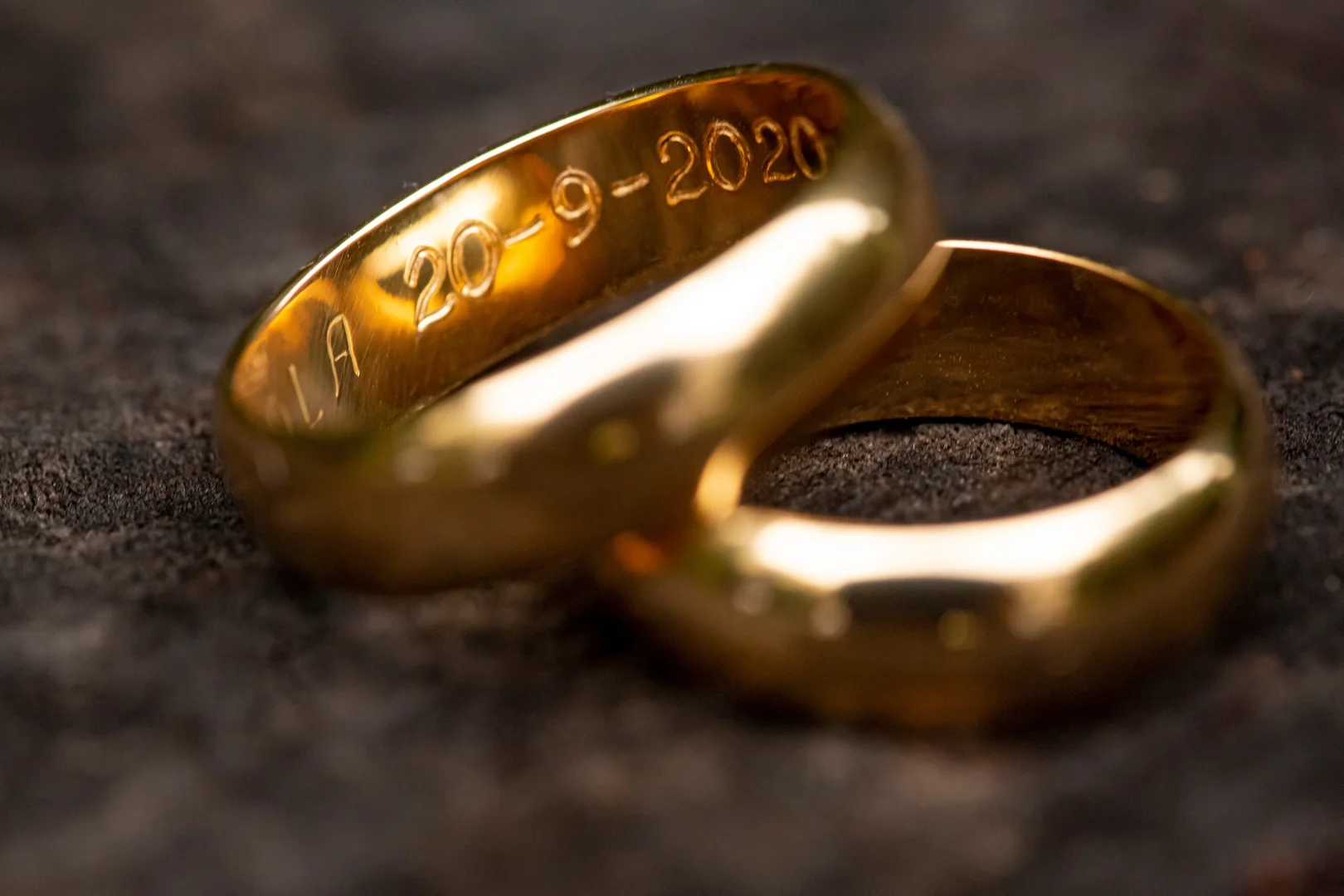 user-inserted Two gold wedding bands with the engraving of a date visible on one.