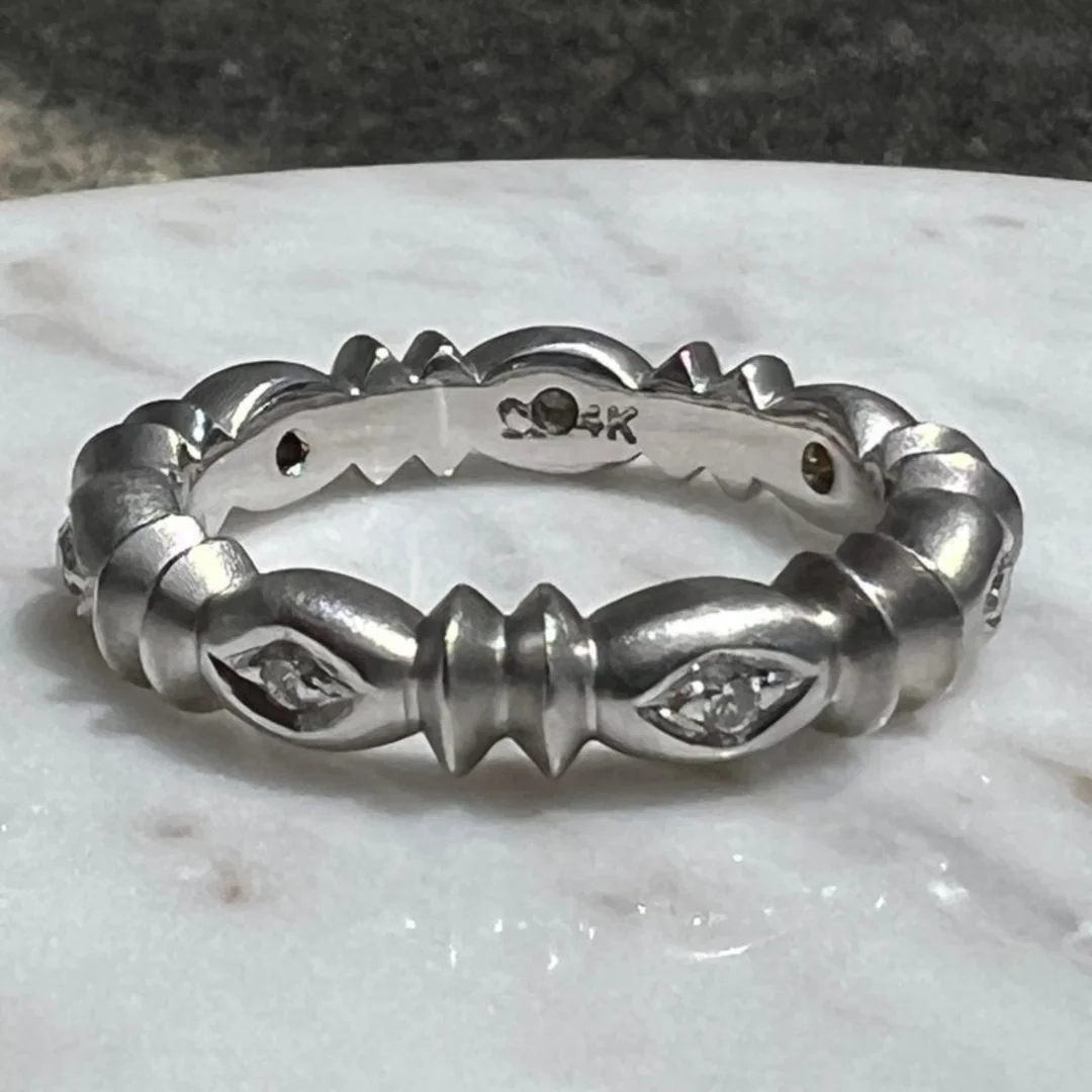 user-inserted An estate 14 karat white gold and diamond eternity band resting on a white marble surface.