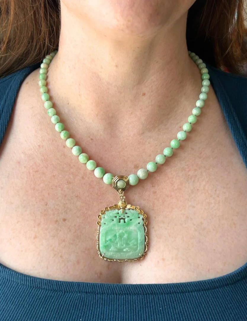An estate carved jade pendant and jade bead necklace worn on a woman's neck.
