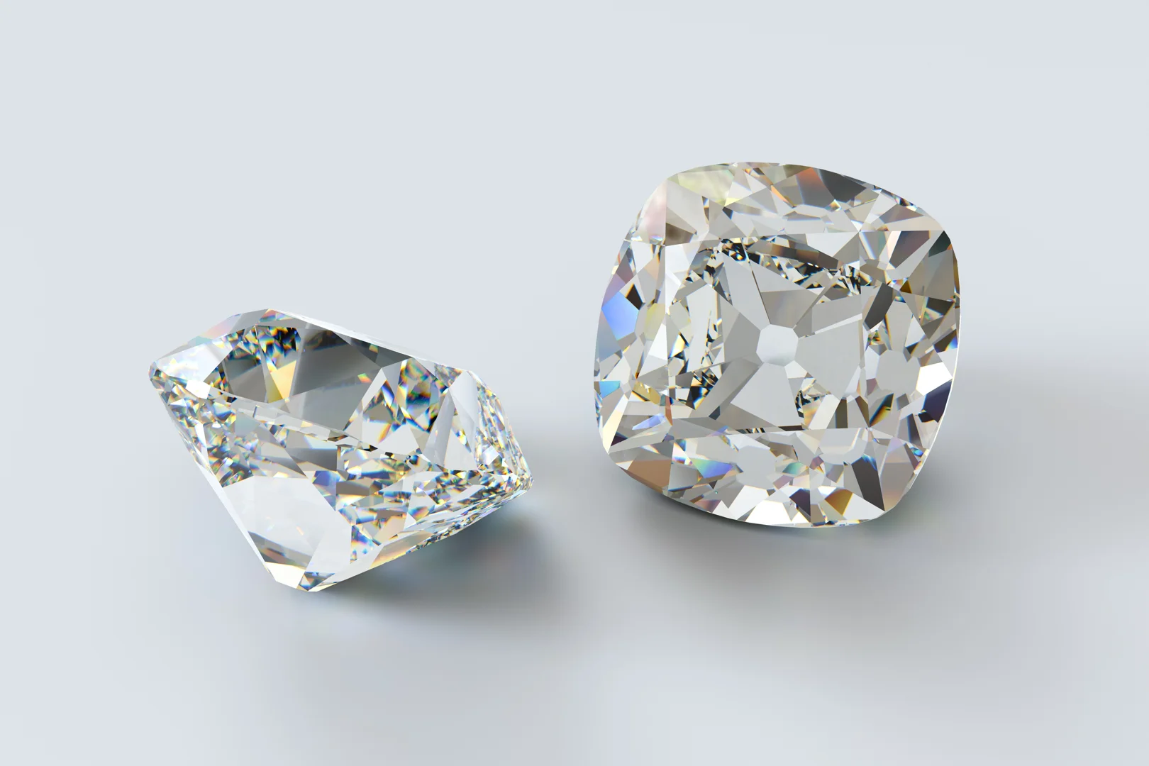 Two loose old mine-cut diamonds on an isolated light grey background.