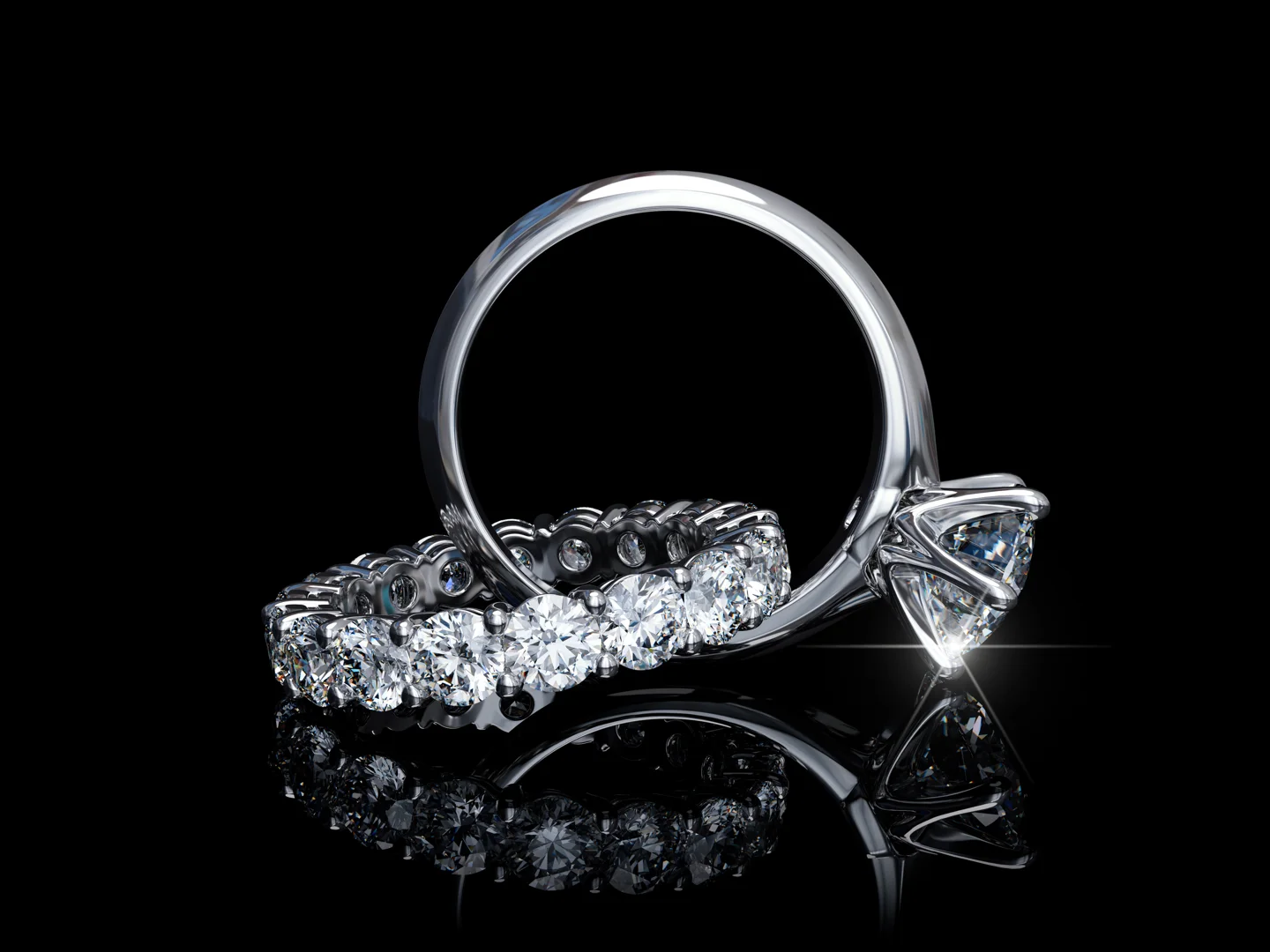 A diamond bridal ring set on a reflective black background. The six-prong diamond solitaire engagement ring has a relatively low center stone profile.