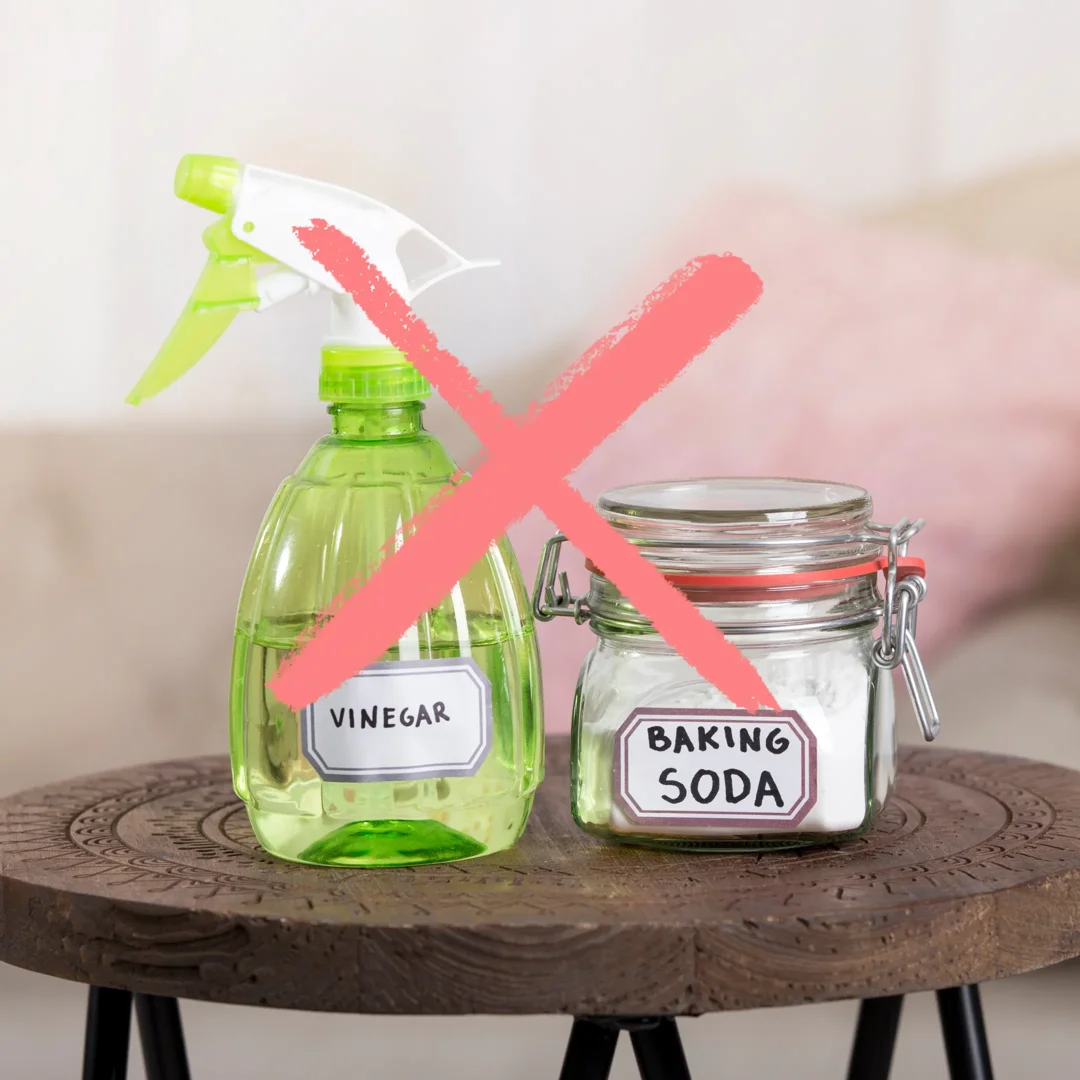 A spray bottle of vinegar and a jar of baking soda with a red X over them to indicate they are not safe to use for jewelry cleaning.