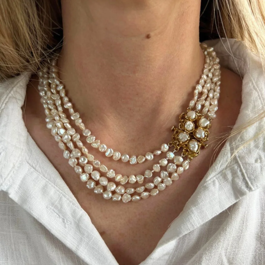 A close-up of a woman's neck wearing a vintage multi-strand Keshi pearl necklace, a possible 12th anniversary jewelry gift.