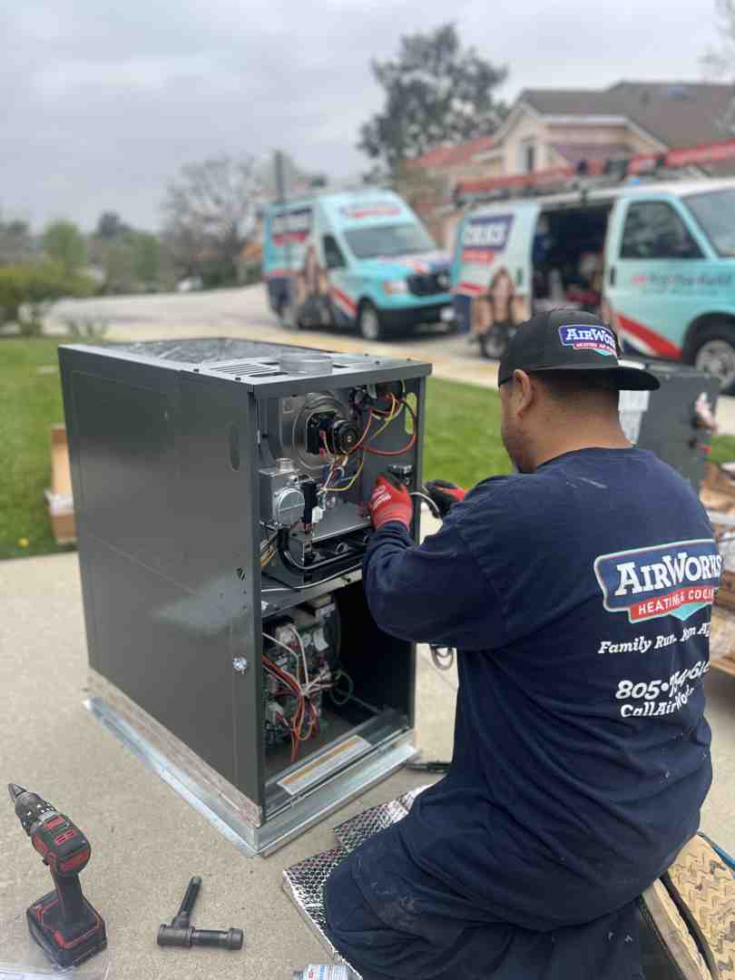 A technician inspecting an outdoor AC unit with tools, focusing on the internal components. - emergency hvac repair moorpark ca