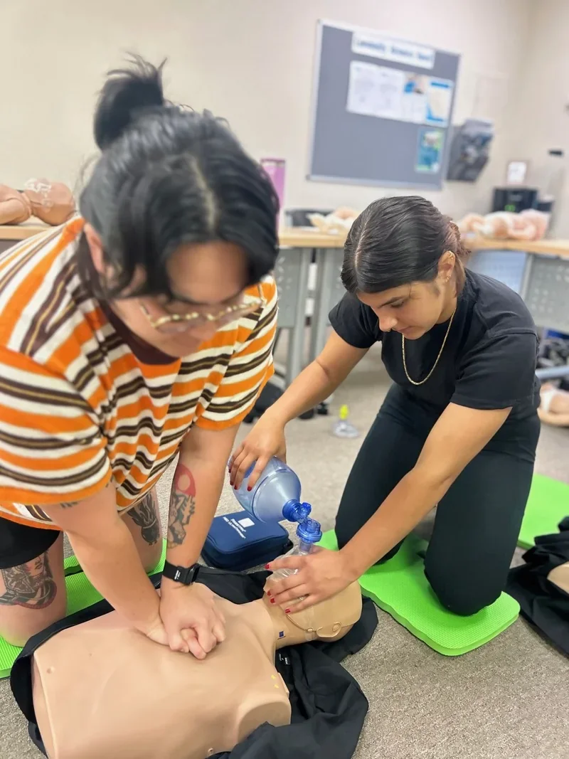Students practice adult CPR compressions and ventilations using a BVM during a BLS certification class.