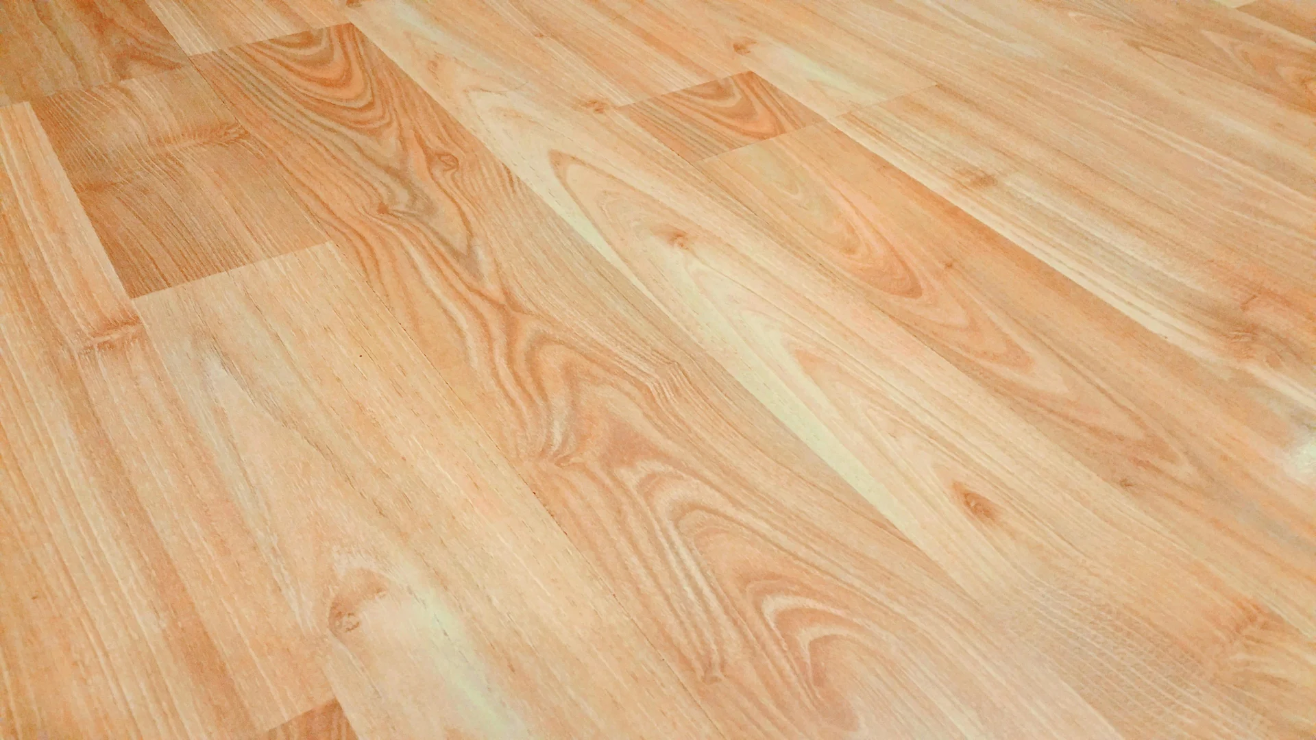 Close-up of light wood laminate flooring with visible grain patterns and plank seams.