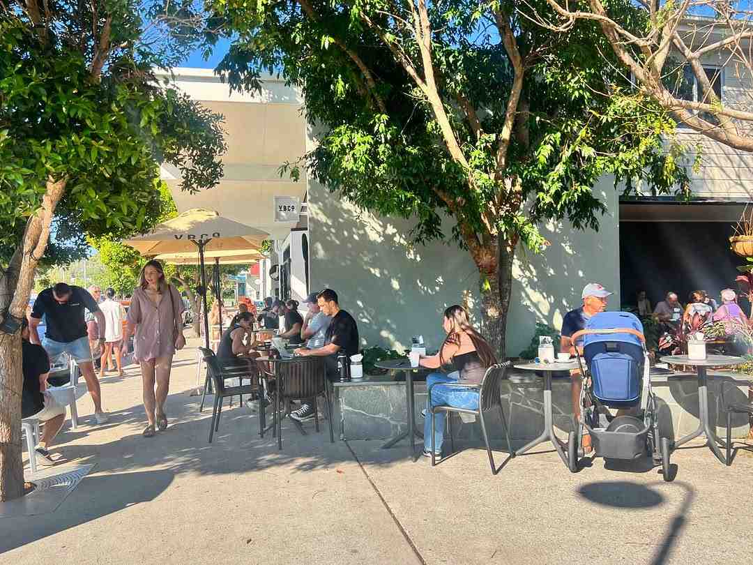 friends sharing coffee and breakfast at outdoor cafe table