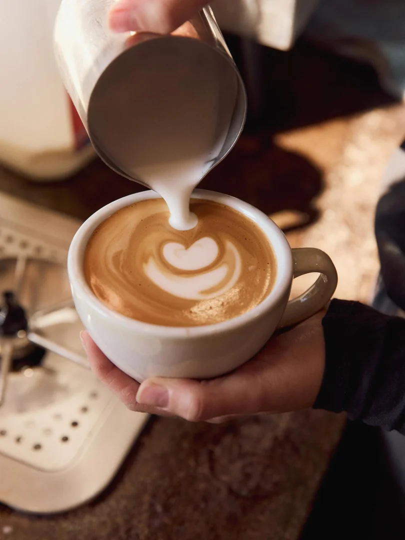 Barista pouring latte art at Flinders Lane Cafe, a popular breakfast spot in Maroochydore.
