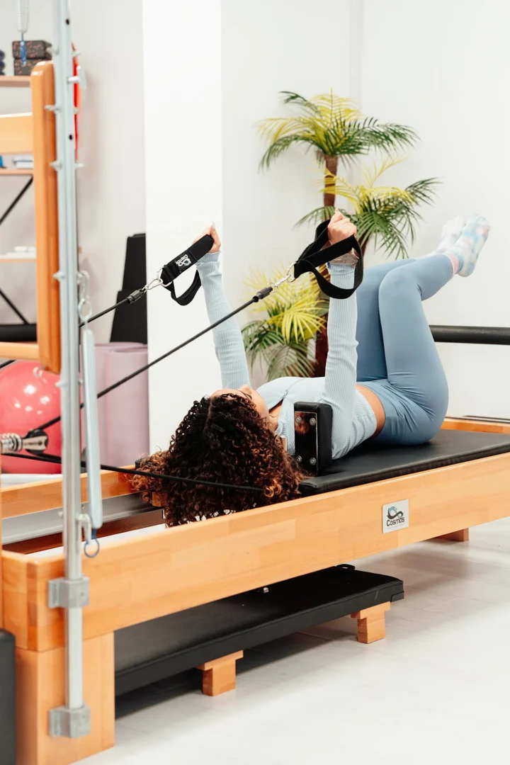 A woman using a Pilates Reformer for core work - Pilates Reformer Training A woman using a Pilates Reformer for core work - Pilates Reformer Training