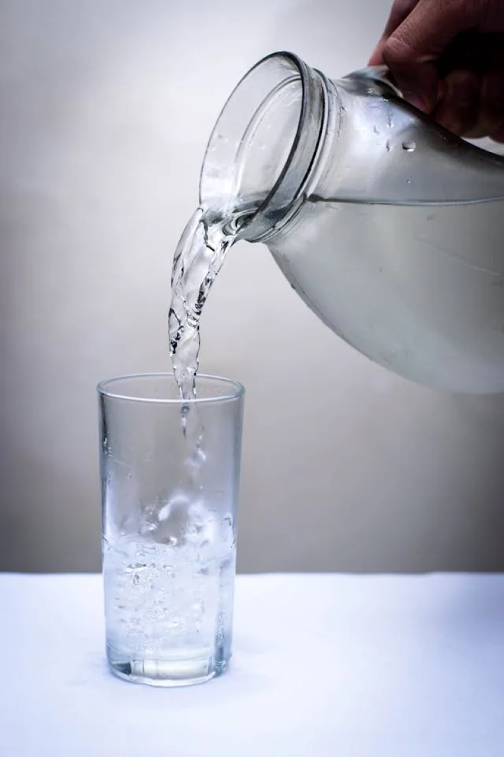 pouring a glass of drinking water from a glass pitcher pouring a glass of drinking water from a glass pitcher
