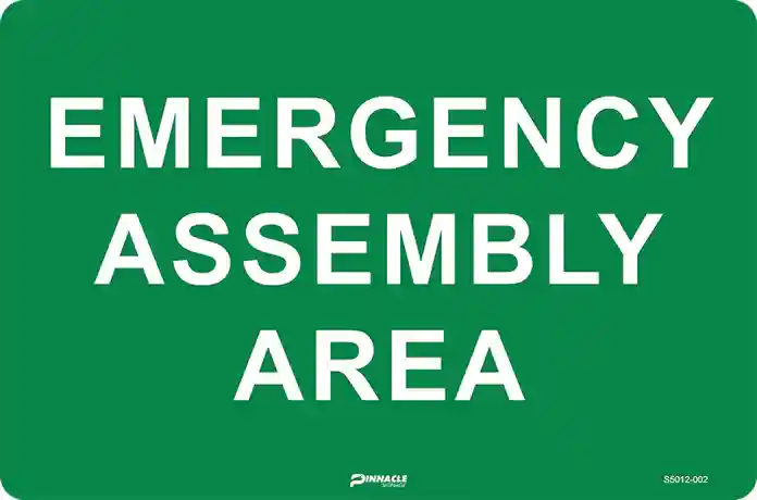 Green and white safety notice reading 'EMERGENCY ASSEMBLY AREA', a clear alternative to a rally point sign