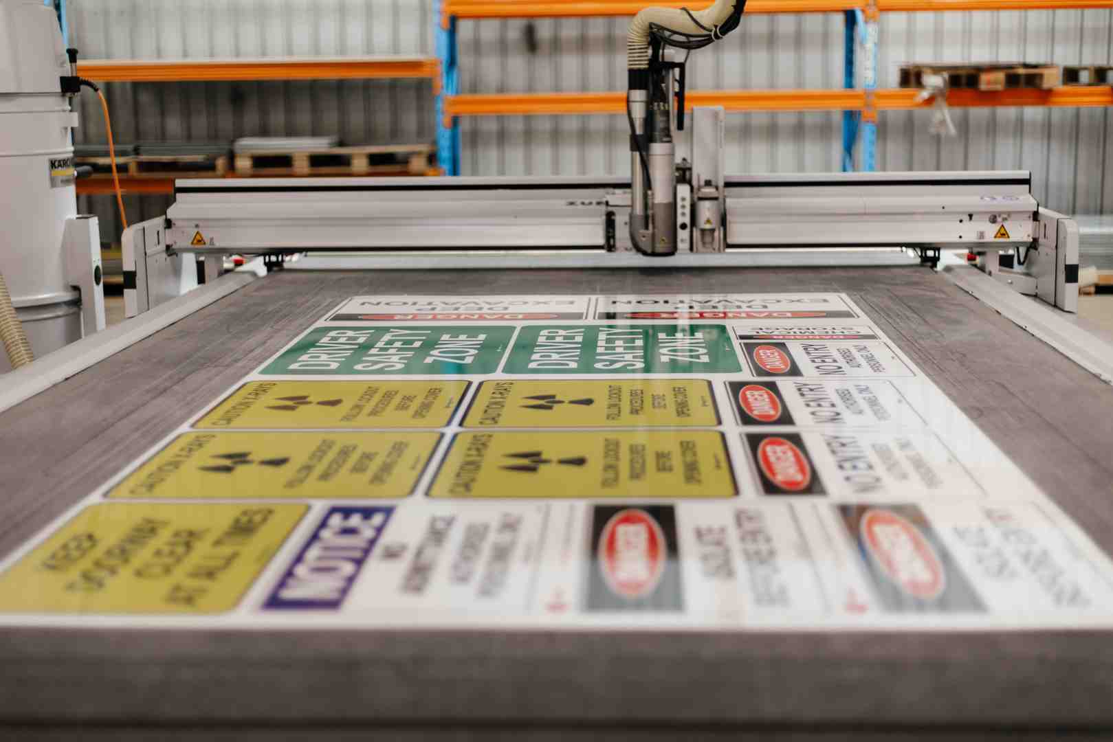Industrial digital cutter preparing various workplace safety and warning decals, ideal for producing a clear first aid kit sign.