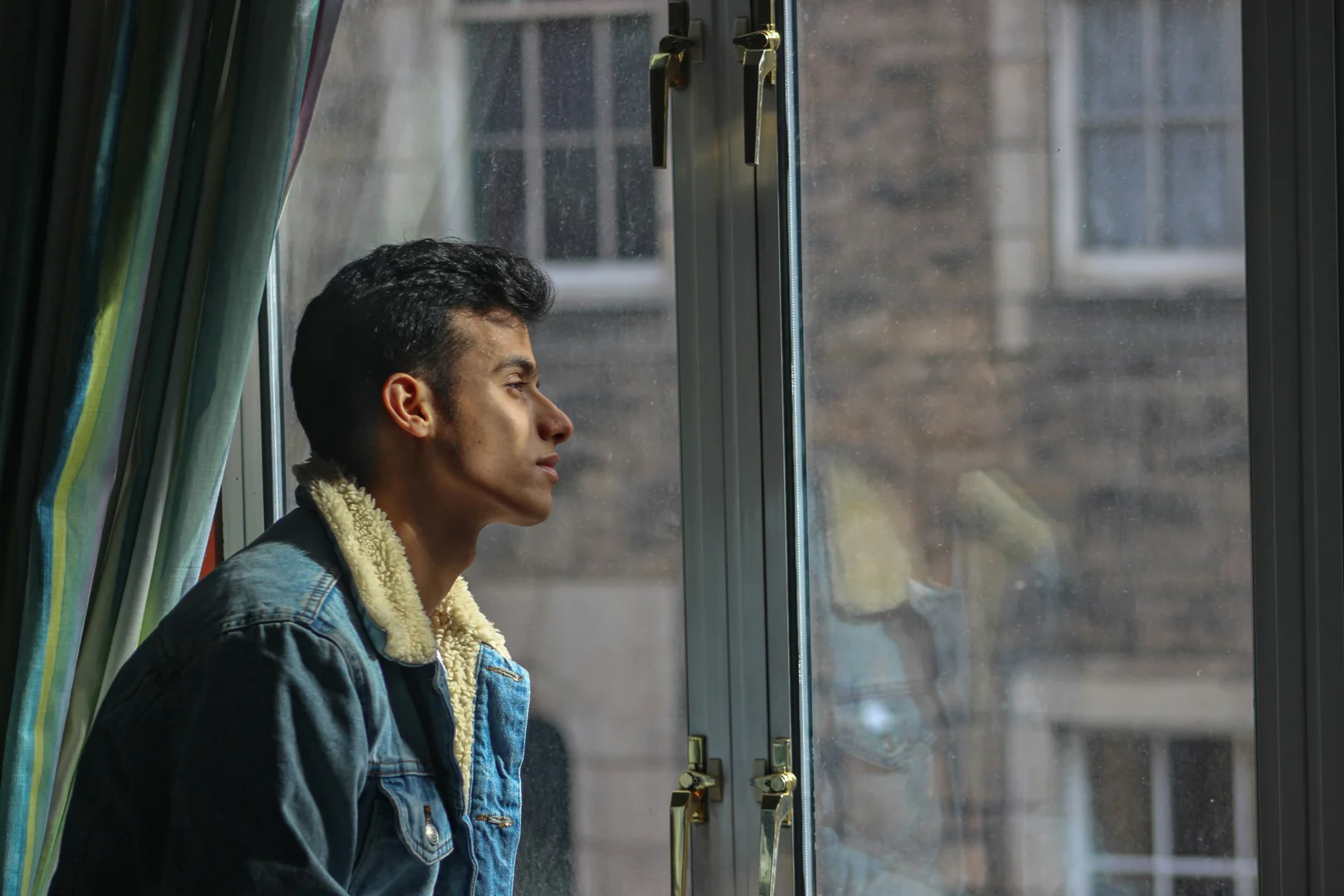 person looking thoughtfully out a window in a city like Valencia or Madrid - sexual therapy person looking thoughtfully out a window in a city like Valencia or Madrid - sexual therapy
