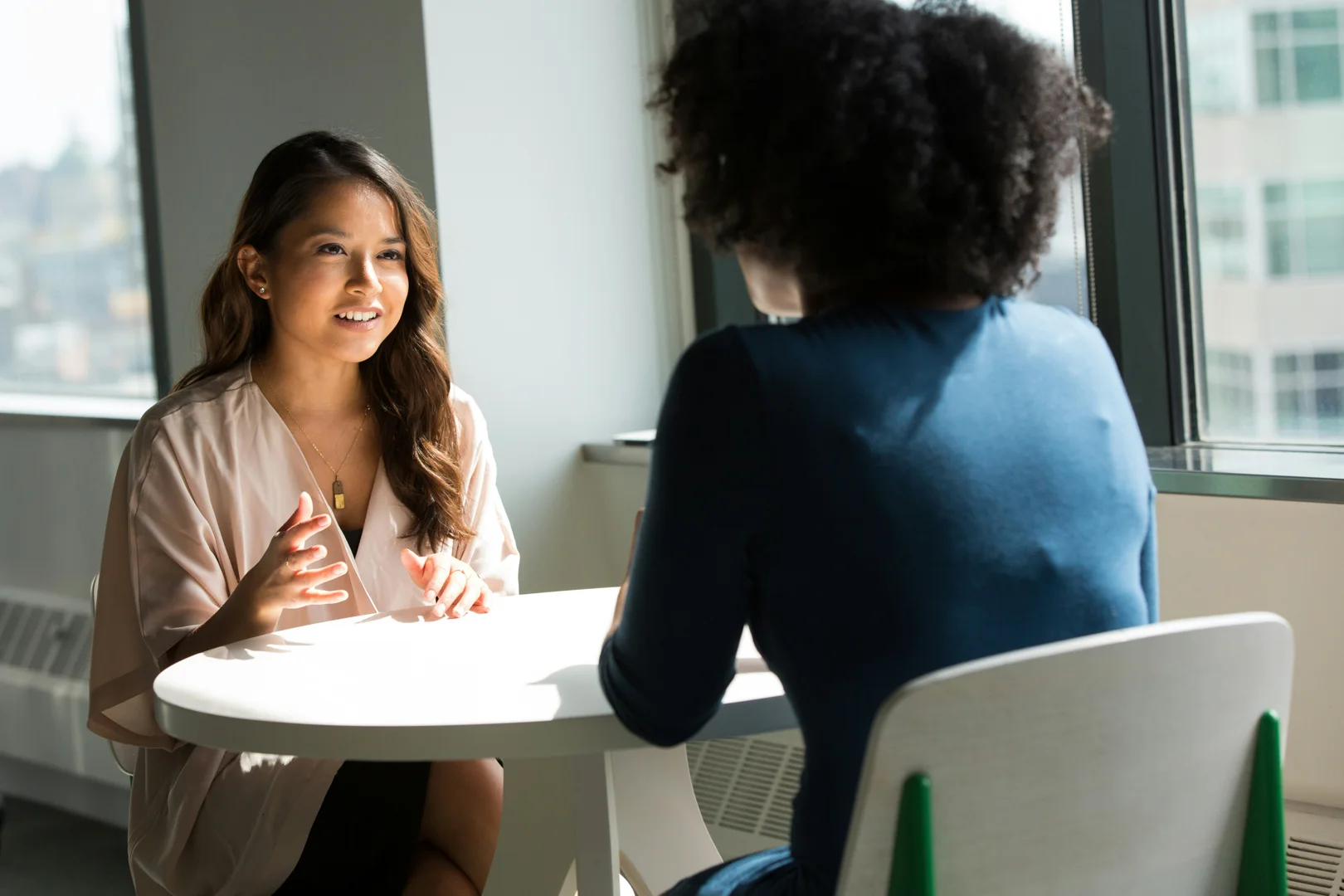 A professional having a supportive coaching-style conversation in a bright Barcelona cafe - expat career coaching