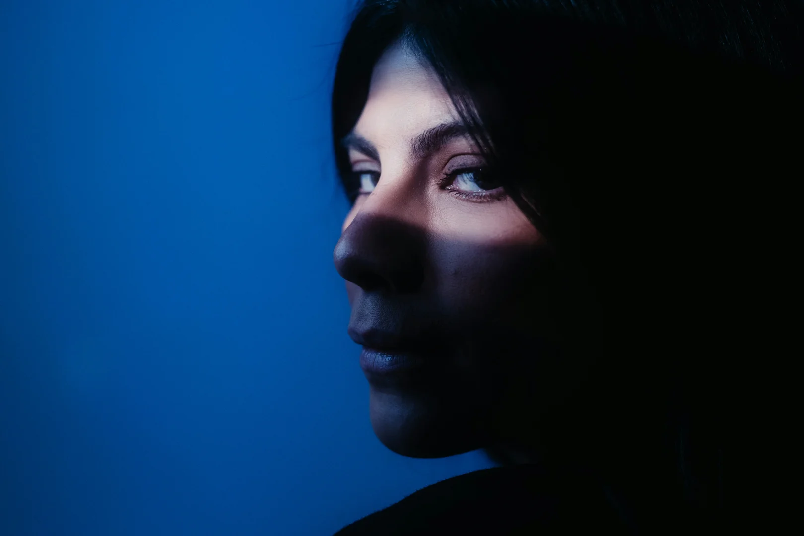 A person sitting quietly in the shadows, looking thoughtful but not hopeless - sexual trauma therapy near me