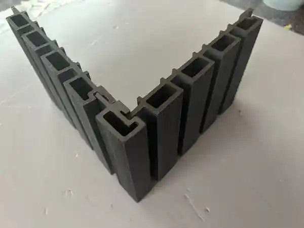 Close-up of dark grey composite corner profile showing the interlocking design and essential cladding accessories needed for a tidy edge.