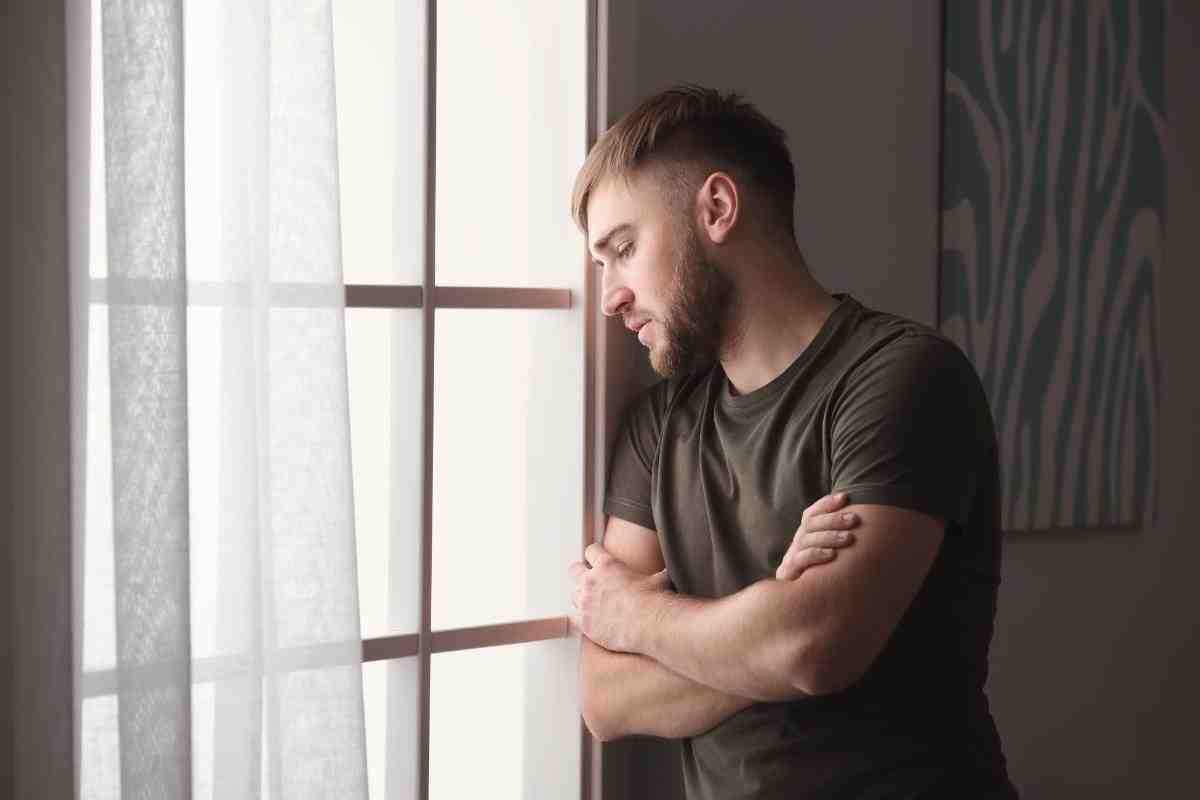 a person looking reflectively out a window - alcohol abuse rehab centers
