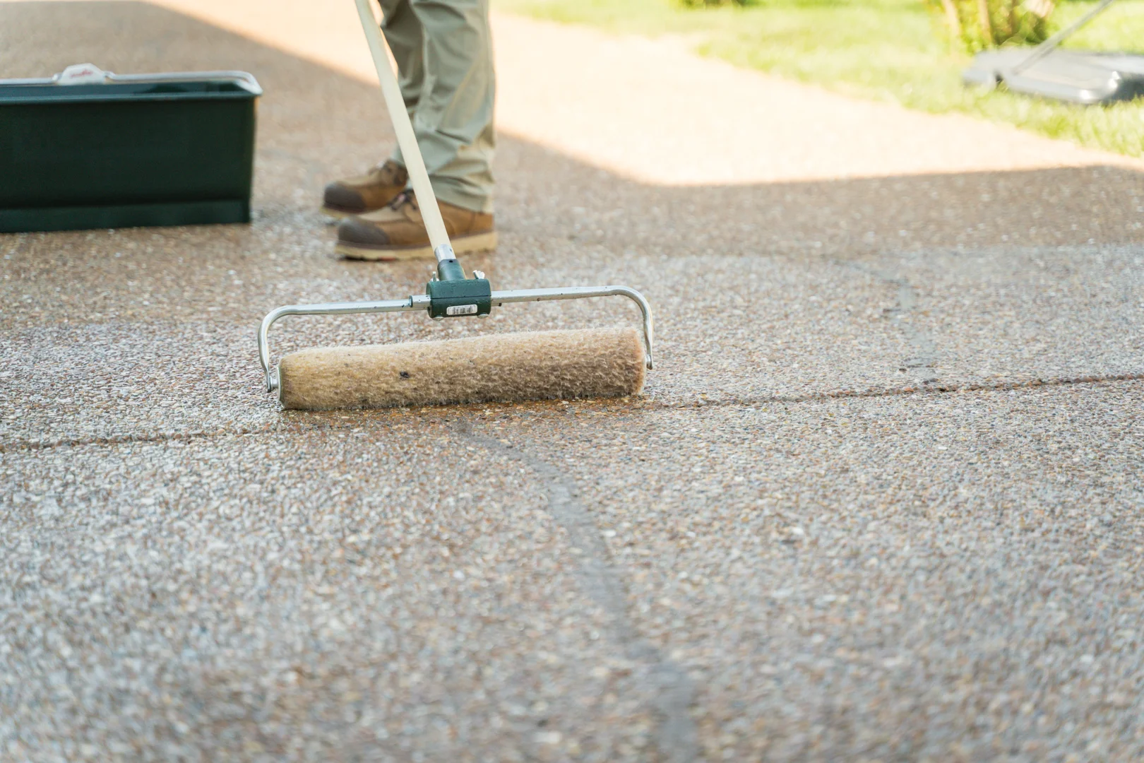 Homeowner applying black crack filler to a driveway crack before sealing Homeowner applying black crack filler to a driveway crack before sealing
