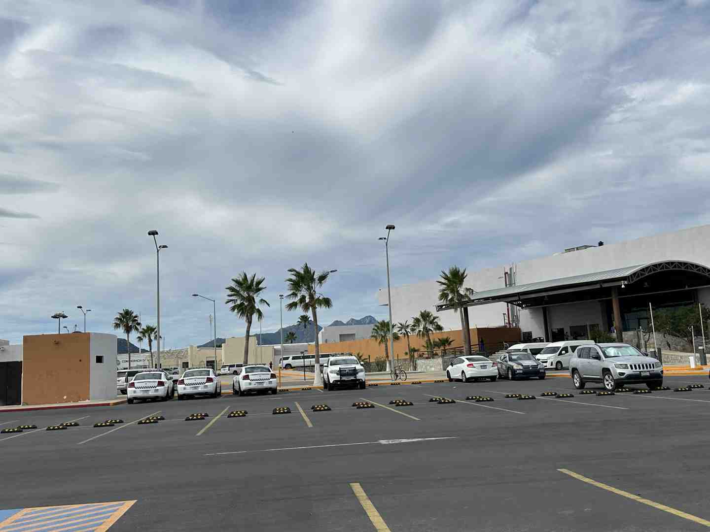 Image of the designated umbrella meeting area outside SJD airport, with people holding signs - airport transfer cabo