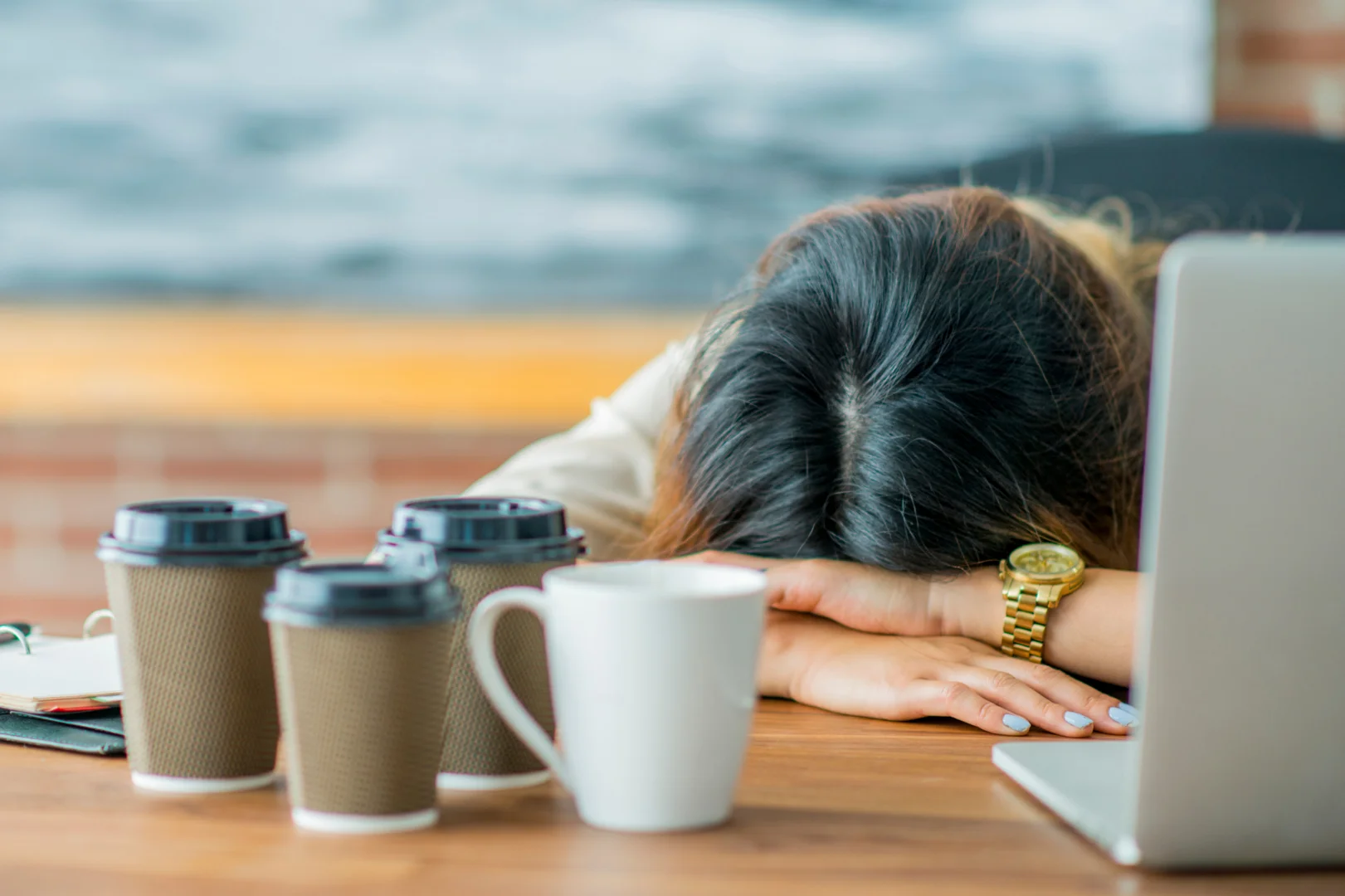 a person keeping her head down on a workig desk wth three coffee cup close by signaling burnout and high-funtioning depression a person keeping her head down on a workig desk wth three coffee cup close by signaling burnout and high-funtioning depression