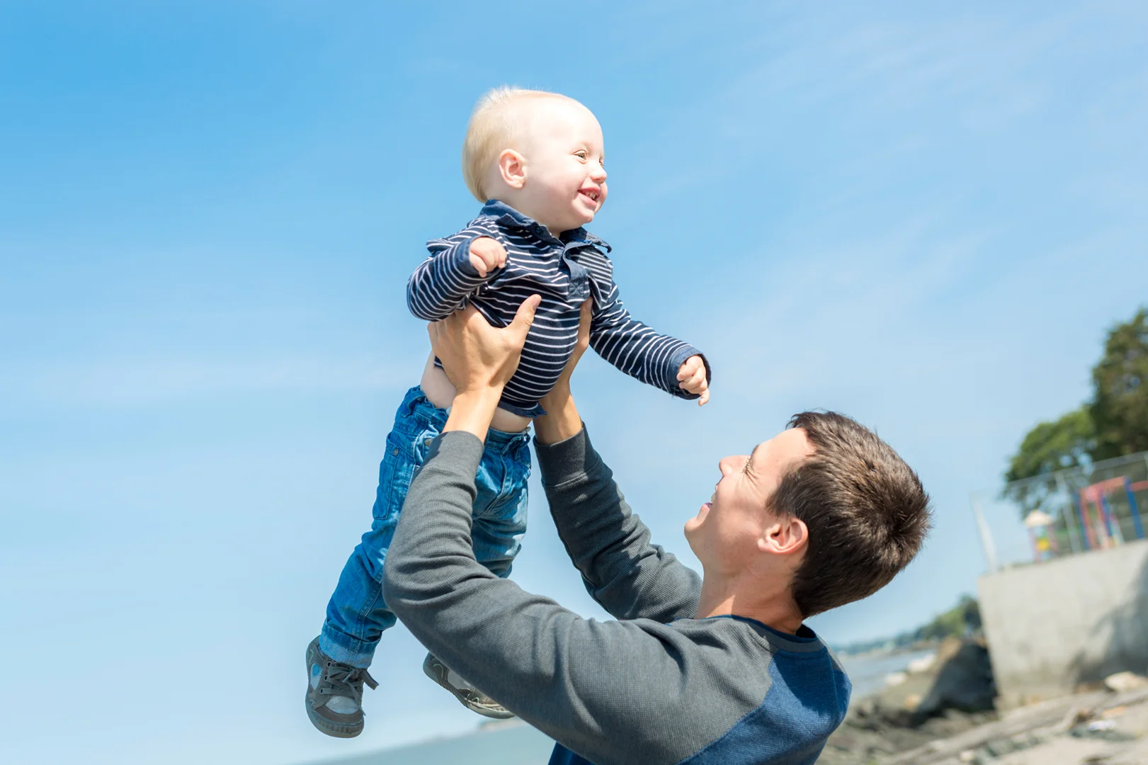 A dad lifting his toddler son to the sky- couples therapy burnout recovery